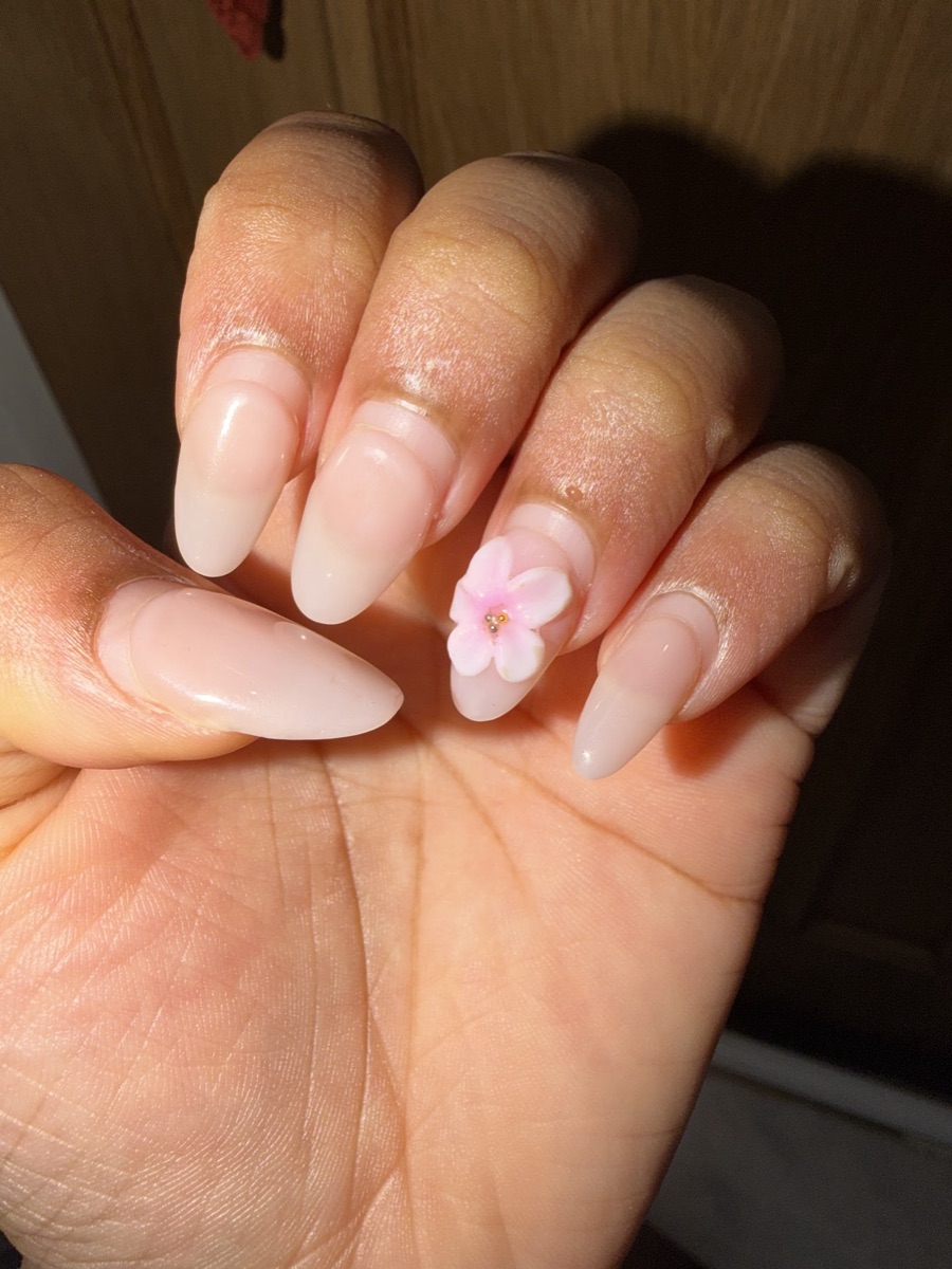 Soft nude almond nails finished with a delicate 3D pink flower accent