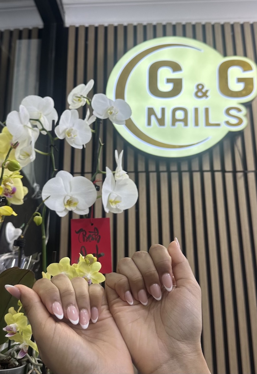 The illuminated G&G Nails sign inside the Gloss&Glow studio with white orchids