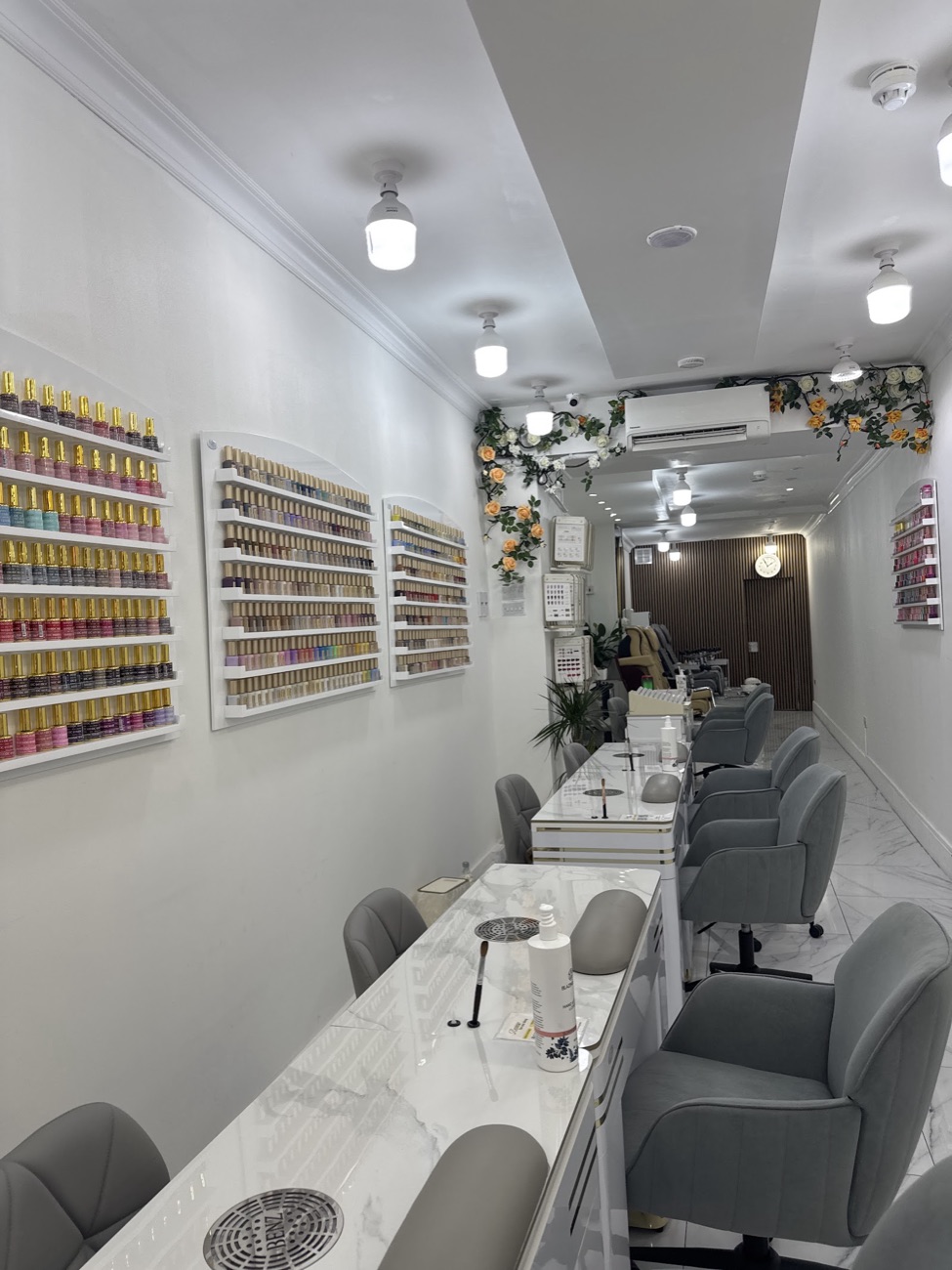 Inside Gloss&Glow Nails — a bright studio with a full wall of gel colours, marble tables and sage velvet chairs